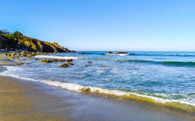 Beautiful rocks cliffs stones boulders and huge big powerful surfer waves on the beach in La Punta Zicatela Puerto Escondido Oaxaca Mexico.