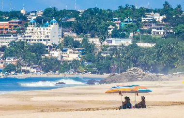 Puerto Escondido Oaxaca Meksika 27. Ocak 2023 Şemsiyeler Şemsiyeler insanları dinlendiriyor Meksikalılar Zicatela Puerto Escondido Oaxaca 'daki tropikal Meksika plajında tatil beldeleri ve dalgalar.