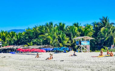 Puerto Escondido Oaxaca Meksika 27. Ocak 2023 Parasols Şemsiyeleri, La Punta Zicatela Puerto Escondido Oaxaca Meksika 'daki tropikal Meksika plajında insanları kaya ve dalgalara boğar..