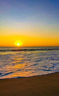 Beautiful stunning colorful and golden sunset in yellow orange red on beach and big huge surfer wave panorama in tropical nature in Zicatela Puerto Escondido Oaxaca Mexico.