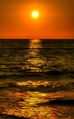 Beautiful stunning colorful and golden sunset in yellow orange red on beach and big huge surfer wave panorama in tropical nature in Zicatela Puerto Escondido Oaxaca Mexico.