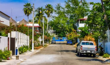 Tipik ve renkli paradisiacal cadde evleri, daireleri restoranları, restoranları, araba dükkanları palmiye ağaçları ve Bacocho ve Rinconada Puerto Escondido Oaxaca Meksika 'daki insanlar..