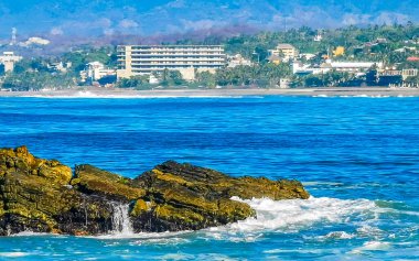 Beautiful rocks cliffs stones and boulders and huge big surfer waves on the beach in La Punta Zicatela Puerto Escondido Oaxaca Mexico.