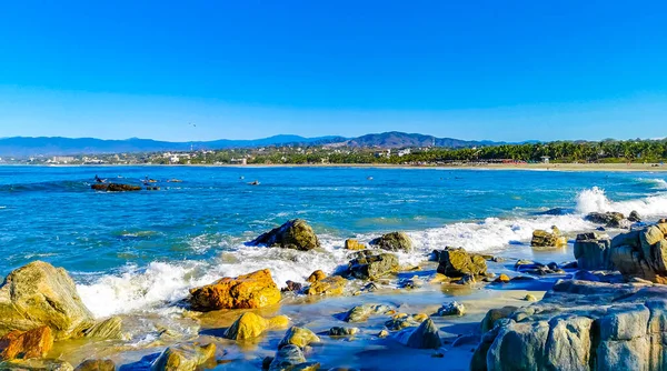 Beautiful rocks cliffs stones and boulders and huge big surfer waves on the beach in La Punta Zicatela Puerto Escondido Oaxaca Mexico.