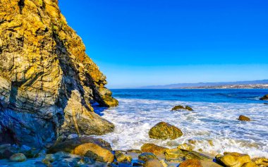 Beautiful rocks cliffs stones and boulders and huge big surfer waves on the beach in La Punta Zicatela Puerto Escondido Oaxaca Mexico.