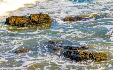 Beautiful rocks cliffs stones and boulders and huge big surfer waves on the beach in La Punta Zicatela Puerto Escondido Oaxaca Mexico.