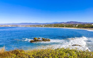 Beautiful tropical and natural city and seascape landscape panorama view with pacific ocean sea palms palm trees and beach with waves of Zicatela Puerto Escondido Oaxaca Mexico.