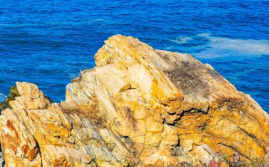 Beautiful rocks cliffs stones and boulders and huge big surfer waves on the beach in La Punta Zicatela Puerto Escondido Oaxaca Mexico.