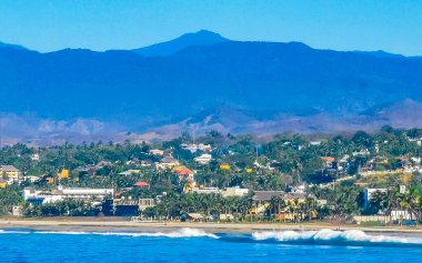 Zicatela Puerto Escondido Oaxaca 'da güneş kumsalı uçurumları dağlar, palmiye ağaçları, mavi sular ve gökyüzü dalgalanır..