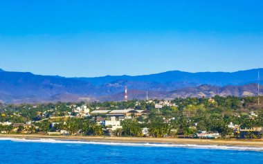 Zicatela Puerto Escondido Oaxaca 'da güneş kumsalı uçurumları dağlar, palmiye ağaçları, mavi sular ve gökyüzü dalgalanır..