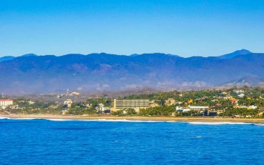 Zicatela Puerto Escondido Oaxaca 'da güneş kumsalı uçurumları dağlar, palmiye ağaçları, mavi sular ve gökyüzü dalgalanır..