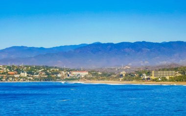 Zicatela Puerto Escondido Oaxaca 'da güneş kumsalı uçurumları dağlar, palmiye ağaçları, mavi sular ve gökyüzü dalgalanır..