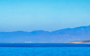 Zicatela Puerto Escondido Oaxaca 'da güneş kumsalı uçurumları dağlar, palmiye ağaçları, mavi sular ve gökyüzü dalgalanır..
