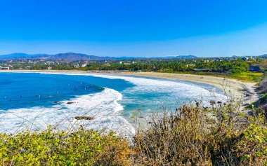 Beautiful tropical and natural city and seascape landscape panorama view with pacific ocean sea palms palm trees and beach with waves of Zicatela Puerto Escondido Oaxaca Mexico.