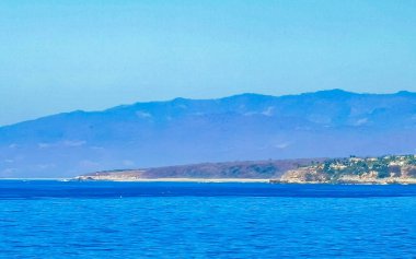 Zicatela Puerto Escondido Oaxaca 'da güneş kumsalı uçurumları dağlar, palmiye ağaçları, mavi sular ve gökyüzü dalgalanır..