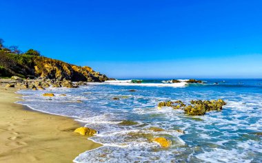 Beautiful rocks cliffs stones and boulders and huge big surfer waves on the beach in La Punta Zicatela Puerto Escondido Oaxaca Mexico.