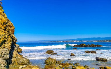 Beautiful rocks cliffs stones and boulders and huge big surfer waves on the beach in La Punta Zicatela Puerto Escondido Oaxaca Mexico.