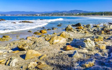 Beautiful rocks cliffs stones and boulders and huge big surfer waves on the beach in La Punta Zicatela Puerto Escondido Oaxaca Mexico.