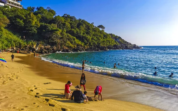 stock image Puerto Escondido Oaxaca Mexico 14. November 2022 Beach sand turquoise blue water rocks cliffs boulders sun loungers people palm trees and huge big surfer waves on the beach Playa Carrizalillo in Puerto Escondido Oaxaca Mexico.