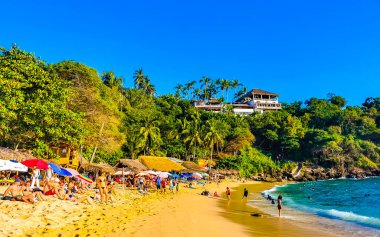 Puerto Escondido Oaxaca Meksika 14. Kasım 2022 Sahil Kum Turkuvaz Mavi Su Kayalıkları Kayalar Güneş Kayaları Palmiye ağaçları ve Playa Carrizalillo sahilinde büyük sörfçü dalgaları Puerto Escondido Oaxaca Meksika.