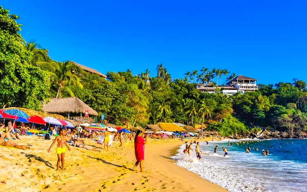 Puerto Escondido Oaxaca Meksika 14. Kasım 2022 Sahil Kum Turkuvaz Mavi Su Kayalıkları Kayalar Güneş Kayaları Palmiye ağaçları ve Playa Carrizalillo sahilinde büyük sörfçü dalgaları Puerto Escondido Oaxaca Meksika.