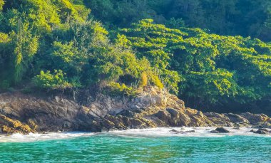 Kumsal turkuvaz mavi su kayaları kayalar kayalar güneş kayaları palmiye ağaçları ve Puerto Escondido Oaxaca 'daki Playa Carrizalillo sahilinde büyük sörfçü dalgaları..