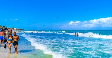 Playa del Carmen Quintana Roo Meksika 17. Nisan 2021 Tropikal Meksika Karayipler plaj manzarası berrak turkuaz mavi sularla insanlar Playa del Carmen Meksika 'daki otellere ve palmiye ağaçlarına gidiyor..