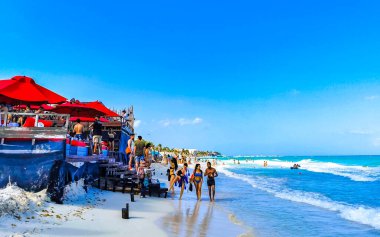Playa del Carmen Quintana Roo Meksika 17. Nisan 2021 Tropikal Meksika Karayipler plaj manzarası berrak turkuaz mavi sularla insanlar Playa del Carmen Meksika 'daki otellere ve palmiye ağaçlarına gidiyor..