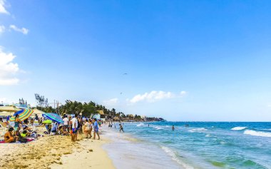 Playa del Carmen Quintana Roo Meksika 17. Nisan 2021 Tropikal Meksika Karayipler plaj manzarası berrak turkuaz mavi sularla insanlar Playa del Carmen Meksika 'daki otellere ve palmiye ağaçlarına gidiyor..