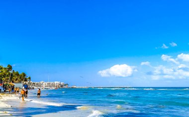 Playa del Carmen Quintana Roo Meksika 17. Nisan 2021 Tropikal Meksika Karayipler plaj manzarası berrak turkuaz mavi sularla insanlar Playa del Carmen Meksika 'daki otellere ve palmiye ağaçlarına gidiyor..