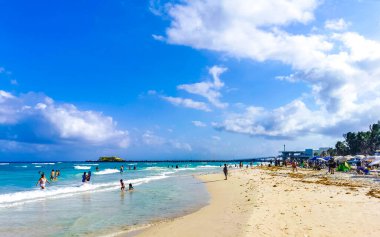 Playa del Carmen Quintana Roo Meksika 17. Nisan 2021 Tropikal Meksika Karayipler plaj manzarası berrak turkuaz mavi sularla insanlar Playa del Carmen Meksika 'daki otellere ve palmiye ağaçlarına gidiyor..
