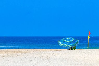 Palmiye ağaçları, şemsiyeler ve güneş şemsiyeleri Zicatela Puerto Escondido Oaxaca Meksika 'daki tropik Meksika plajındaki sahil tatil beldesi otelinde..