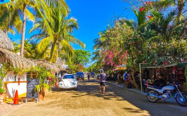 Puerto Escondido Oaxaca Meksika 27. Ocak 2023 İnsanların bulunduğu tipik renkli turist caddesi Zicatela Puerto Escondido Oaxaca Meksika 'daki La Punta' da restoran dükkanları, arabalar ve bar..