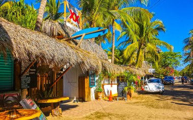 Puerto Escondido Oaxaca Meksika 27. Ocak 2023 İnsanların bulunduğu tipik renkli turist caddesi Zicatela Puerto Escondido Oaxaca Meksika 'daki La Punta' da restoran dükkanları, arabalar ve bar..