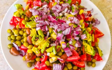 Meksika 'da çatallı veya kaşıklı beyaz bir tabak üzerinde bezelyeli vejetaryen yemeği, bezelye, patates, soğan ve sarımsak..