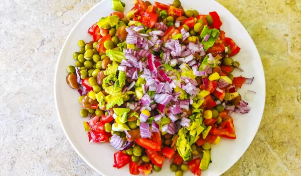 Vegetable vegan dish with beans peas potatoes onions tomato and garlic on a white plate bowl with fork or spoon in Mexico.