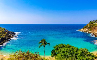 Kumsal turkuvaz mavi su kayaları kaya kayaları palmiye ağaçları büyük sörfçü dalgaları ve Puerto Escondido Oaxaca 'daki Playa Carrizalillo plajı manzarası.