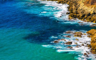 Kumsal turkuvaz mavi su kayaları kaya kayaları palmiye ağaçları büyük sörfçü dalgaları ve Puerto Escondido Oaxaca 'daki Playa Carrizalillo plajı manzarası.