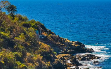 Kumsal turkuvaz mavi su kayaları kaya kayaları palmiye ağaçları büyük sörfçü dalgaları ve Puerto Escondido Oaxaca 'daki Playa Carrizalillo plajı manzarası.