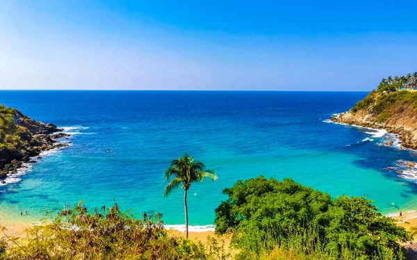 stock image Beach sand turquoise blue water rocks cliffs boulders palm trees huge big surfer waves and panorama view on the beach Playa Carrizalillo in Puerto Escondido Oaxaca Mexico.