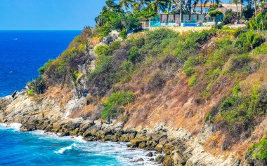 Kumsal turkuvaz mavi su kayaları kaya kayaları palmiye ağaçları büyük sörfçü dalgaları ve Puerto Escondido Oaxaca 'daki Playa Carrizalillo plajı manzarası.