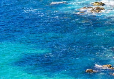 Kumsal turkuvaz mavi su kayaları kaya kayaları palmiye ağaçları büyük sörfçü dalgaları ve Puerto Escondido Oaxaca 'daki Playa Carrizalillo plajı manzarası.