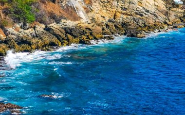 Kumsal turkuvaz mavi su kayaları kaya kayaları palmiye ağaçları büyük sörfçü dalgaları ve Puerto Escondido Oaxaca 'daki Playa Carrizalillo plajı manzarası.