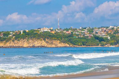 Puerto Escondido Oaxaca Meksika 13. Kasım 2022 'de güneş kumsalı insanları sörf yapıyor Palmiye ağaçları, plaj barı ve Zicatela Puerto Escondido Oaxaca' da mavi su dalgaları..