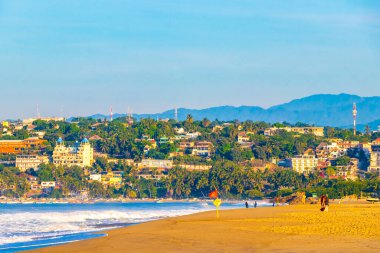 Puerto Escondido Oaxaca Meksika 16. Kasım 2022 'de güneş kumsalı insanları sörf yapıyor Palmiye ağaçları, plaj barı ve Zicatela Puerto Escondido Oaxaca' da mavi su dalgaları..