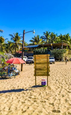 Puerto Escondido Oaxaca Meksika 27. Mart 2023 'te, Zicatela Puerto Escondido Oaxaca Meksika' da palmiye ağaçları, turizm plaj barı ve mavi su dalgaları sörfçüleri yapar..