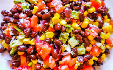 Fasulyeli sebze yemeği patates soğanlı avokado domates ve sarımsak Meksika 'da çatal veya kaşıkla beyaz bir tabak üzerinde..