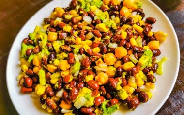 Fasulyeli sebze yemeği patates soğanlı avokado domates ve sarımsak Meksika 'da çatal veya kaşıkla beyaz bir tabak üzerinde..