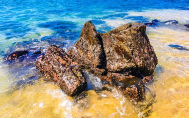 Plaj kumsalı turkuvaz mavi su kayaları kaya kayaları palmiye ağaçları büyük sörfçü dalgaları ve plaj manzarası Playa Manzanillo ve Puerto Angelito Puerto Escondido Oaxaca Meksika.