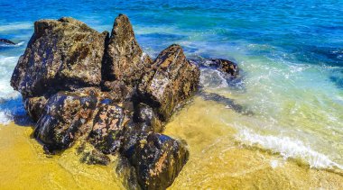 Plaj kumsalı turkuvaz mavi su kayaları kaya kayaları palmiye ağaçları büyük sörfçü dalgaları ve plaj manzarası Playa Manzanillo ve Puerto Angelito Puerto Escondido Oaxaca Meksika.